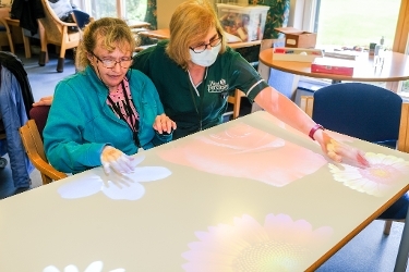 A photograph of people using the Tovertafel, an interactive piece of equipment, at Greenfield House Resource Centre